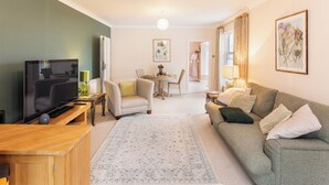 Uma sala de estar com televisão, sofá e espaço de refeições.