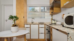 A compact kitchen with white cabinets, a wooden countertop, a built-in microwave, and a potted plant. - Vibrant Cascades Studio | Balcony | WiFi (Cape Town)