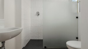 A bathroom with a white sink, a shower with a glass door, and a toilet. - Vibrant Cascades Studio | Balcony | WiFi (Cape Town)