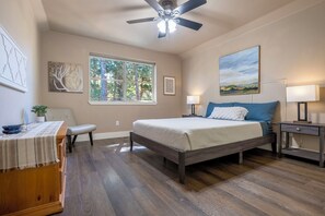 Relax in this serene bedroom with a large bed, ceiling fan, and a window offering a view of the outdoors.