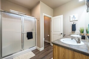 Enjoy a refreshing shower in the glass-enclosed shower, paired with a convenient sink and mirror.