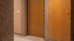 Un pasillo con puerta de madera, paredes de granito y suelo de baldosas.