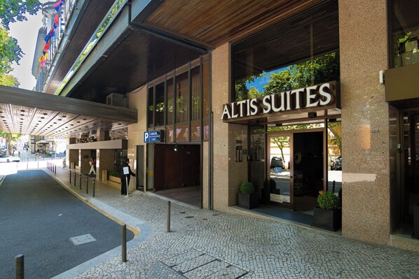 Exterior del Altis Suites, con una fachada moderna con amplios ventanales y una entrada destacada.