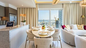 Una habitación de hotel moderna con comedor, sofá y vista a la ciudad.