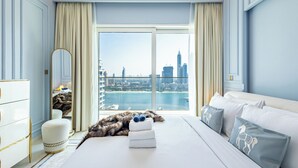Habitación de hotel con una cama grande, un espejo, vistas de la ciudad y un horizonte urbano a través de la ventana.