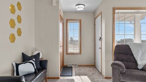 A modern living room with a black leather sofa, a grey armchair, and a coffee table. There is a door leading to another room, a small window, and a light fixture on the ceiling. - Fireplace! Fully Fenced Yard! (Green Bay)