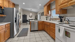 A modern kitchen with wooden cabinets, stainless steel appliances, and a central island. - Fireplace! Fully Fenced Yard! (Green Bay)