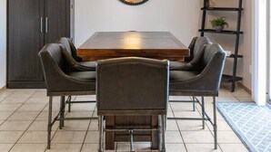 A dining area with a wooden table, four chairs, a pendant light fixture, a cabinet, and a shelving unit. - Fireplace! Fully Fenced Yard! (Green Bay)