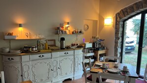 Une cuisine chaleureuse avec des meubles blancs, une machine à café et un coin repas comprenant une table et des chaises.