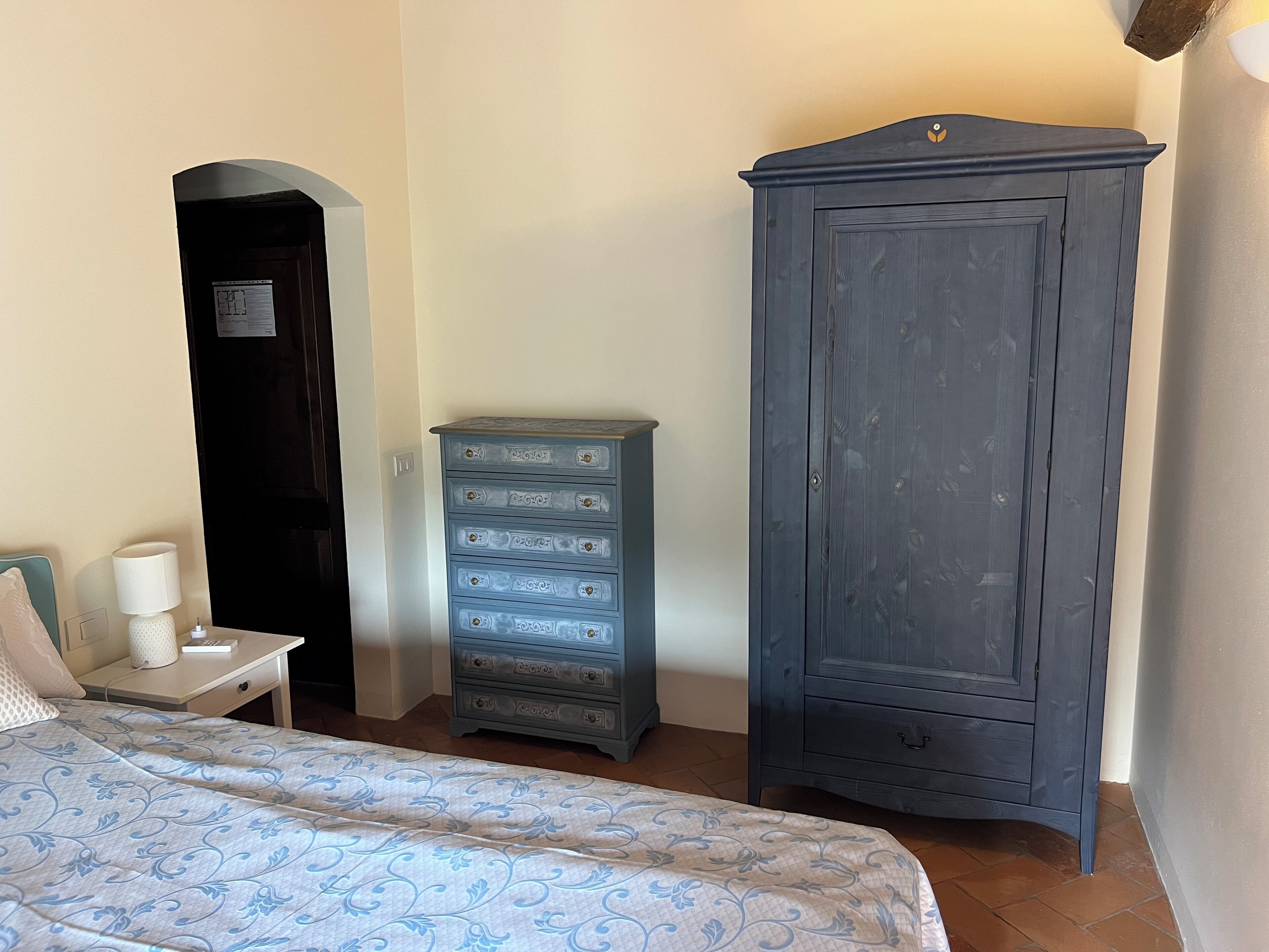 A bedroom with a bed, a dresser, a nightstand, and a wardrobe.