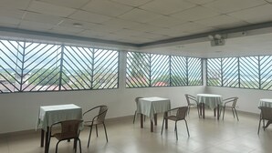 A spacious room with large windows, multiple tables, and chairs arranged for dining. - DORAL INN HOTEL (Iquitos)