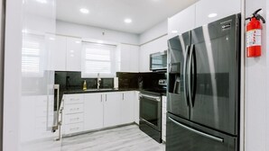 A modern kitchen with white cabinets, stainless steel appliances, and a black countertop.