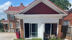 Una casa de techo rojo, un porche cubierto y un camino de entrada de grava.