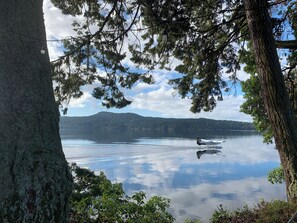 Un lac paisible dont les eaux reflètent clairement les arbres et les montagnes qui se dressent à l’arrière-plan.
