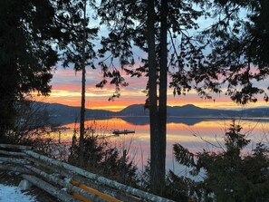 Une vue paisible sur un lac, avec une jetée en bois et des arbres qui encadrent le paysage.