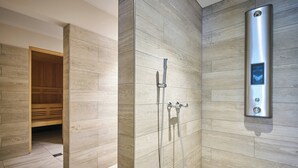 A modern bathroom with a wooden panel wall, a built-in sauna, and a wall-mounted shower control panel.