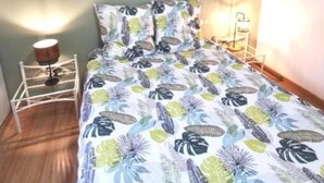 Un dormitorio con cama, mesita de noche, lámpara y un cuadro en la pared.
