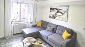 A modern living room with a grey sectional sofa, a small round table, and a patterned rug.