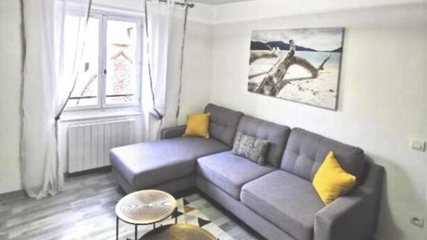 Una sala moderna con un sofá seccional gris, una mesita redonda y un tapete estampado.