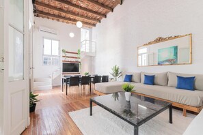 Uma sala de estar moderna com sofá, mesa de centro e área de jantar.