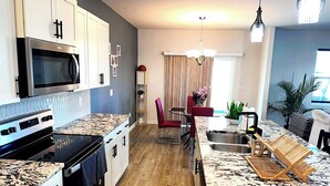 A modern kitchen with granite countertops, a built-in microwave, and a stainless steel range hood. - Simple Elegant Single Fam Home < DT Raleigh NCSU (Raleigh)