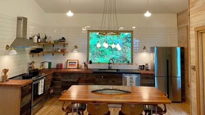 Una cocina moderna con una mesa de comedor de madera, electrodomésticos integrados e iluminaci ón colgante.
