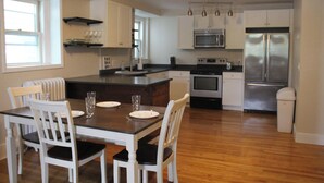 A modern kitchen with white cabinetry, a central island, and stainless steel appliances.