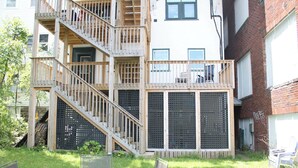 A multi-story building with a wooden deck and a staircase leading to an upper level.