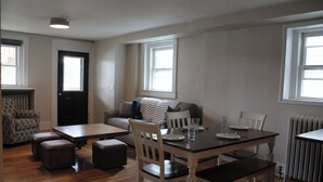 A living room with a dining table, chairs, a sofa, and a patterned armchair.