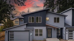 A modern two-story house with a garage, a front porch, and a well-maintained lawn. - Modern and cozy home on Lakeview (Lake Oswego)