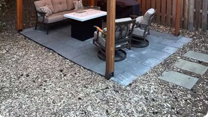 A covered outdoor seating area with a wooden pergola, string lights, a cushioned sofa, and a coffee table. - Modern and cozy home on Lakeview (Lake Oswego)