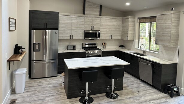 A modern kitchen with dark cabinetry, a stainless steel refrigerator, a microwave, a toaster, and a sink. - Modern and cozy home on Lakeview (Lake Oswego)
