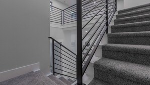A modern staircase with a metal railing and carpeted steps. - Modern and cozy home on Lakeview (Lake Oswego)