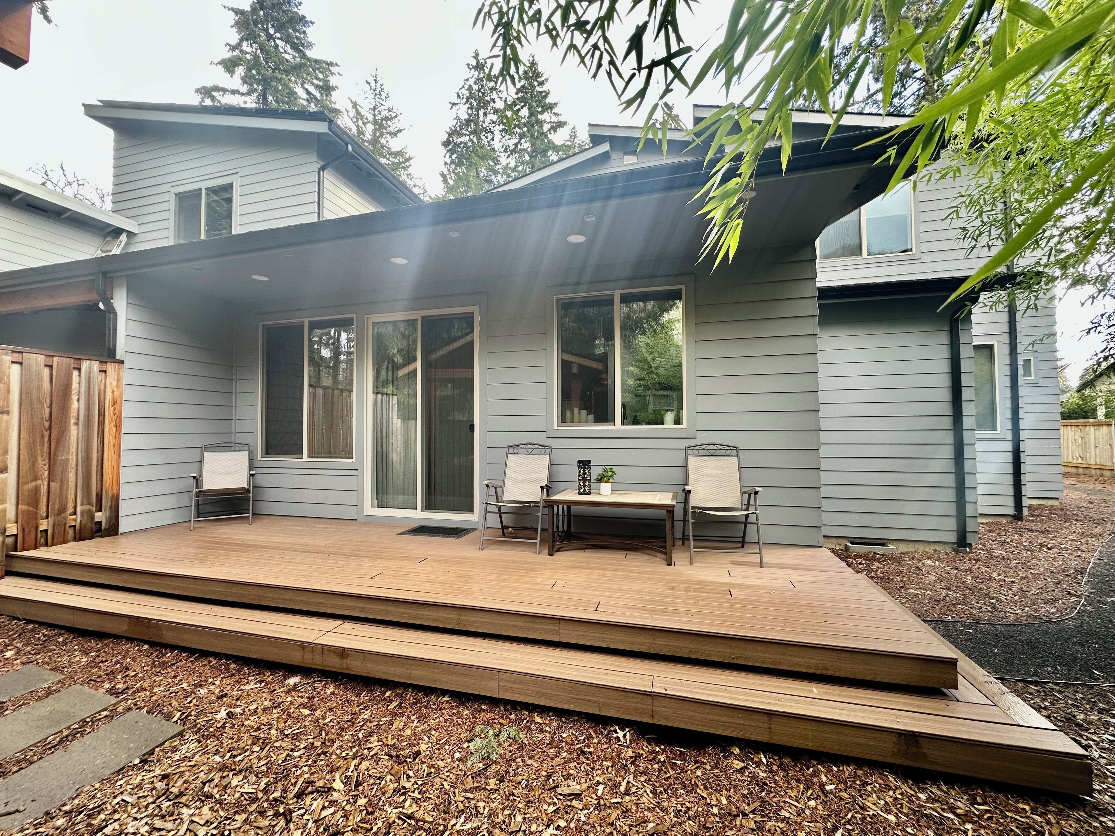 Une maison moderne dotée d’un patio couvert, de grandes fenêtres et d’une terrasse en bois.
