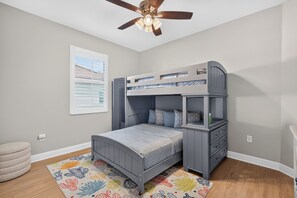 A child's bunk bed with a desk, a ceiling fan, and a window with blinds. - Villa Flamingo – Tropical Waterfront Retreat with Heated Saltwater Pool (Cape Coral)