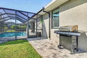 A backyard with a swimming pool, a covered patio, and a barbecue grill. - Villa Flamingo – Tropical Waterfront Retreat with Heated Saltwater Pool (Cape Coral)