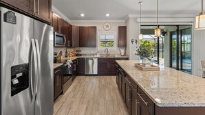 Una cocina moderna con electrodomésticos de acero inoxidable, armarios de madera oscura y encimera de granito.