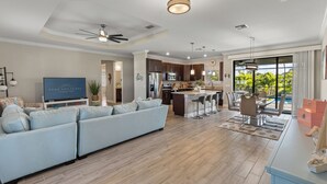 Un salón amplio con sofá modular, televisor de pantalla plana y ventilador de techo.