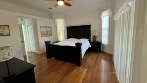 A bedroom with a bed, a nightstand, a ceiling fan, and a window with curtains.