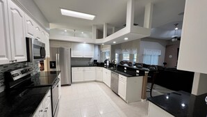 A modern kitchen with white cabinetry, stainless steel appliances, and black countertops.