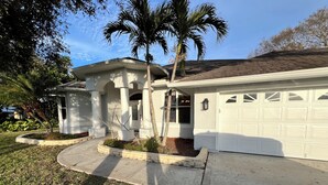 A house with a garage, a covered porch, and a well-maintained lawn.