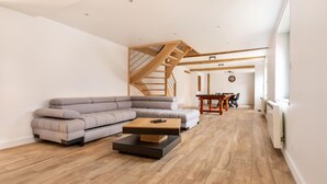 En moderne stue med en grå modulsofa, et træsofabord og et spiseområde med et træbord og stole.
