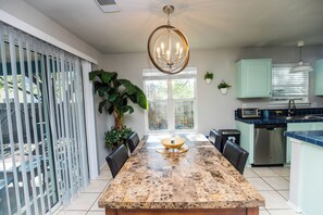 Una cocina moderna con encimera de granito, electrodomésticos de acero inoxidable y un comedor con una mesa grande y sillas.