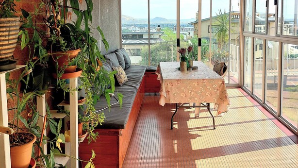 Ein Balkon mit einer Couch, einem Tisch und Topfpflanzen.