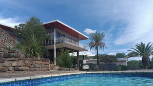 Ein Schwimmbad mit einer Steinmauer und einem Haus mit Balkon.