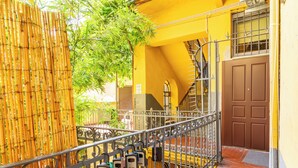 A yellow building with a metal staircase and a brown door. - Teo's House - Navigli Apartments (Milano)
