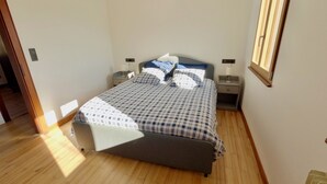 A bedroom with a bed, two bedside tables, a nightstand, and a window.