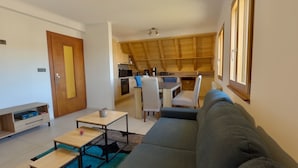 A modern living room with a sofa, a coffee table, and a dining area with chairs.