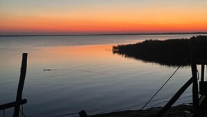 A calm body of water with a sunset in the background, a dock, and a small boat. - Beautiful home in Miedzyzdroje with sauna (Miedzyzdroje)