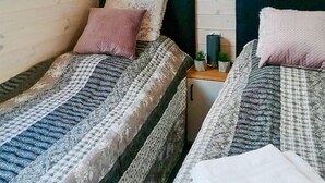 Two single beds with patterned bedding, a small bedside table with a plant, and a white wall with a window. - Beautiful home in Miedzyzdroje with sauna (Miedzyzdroje)